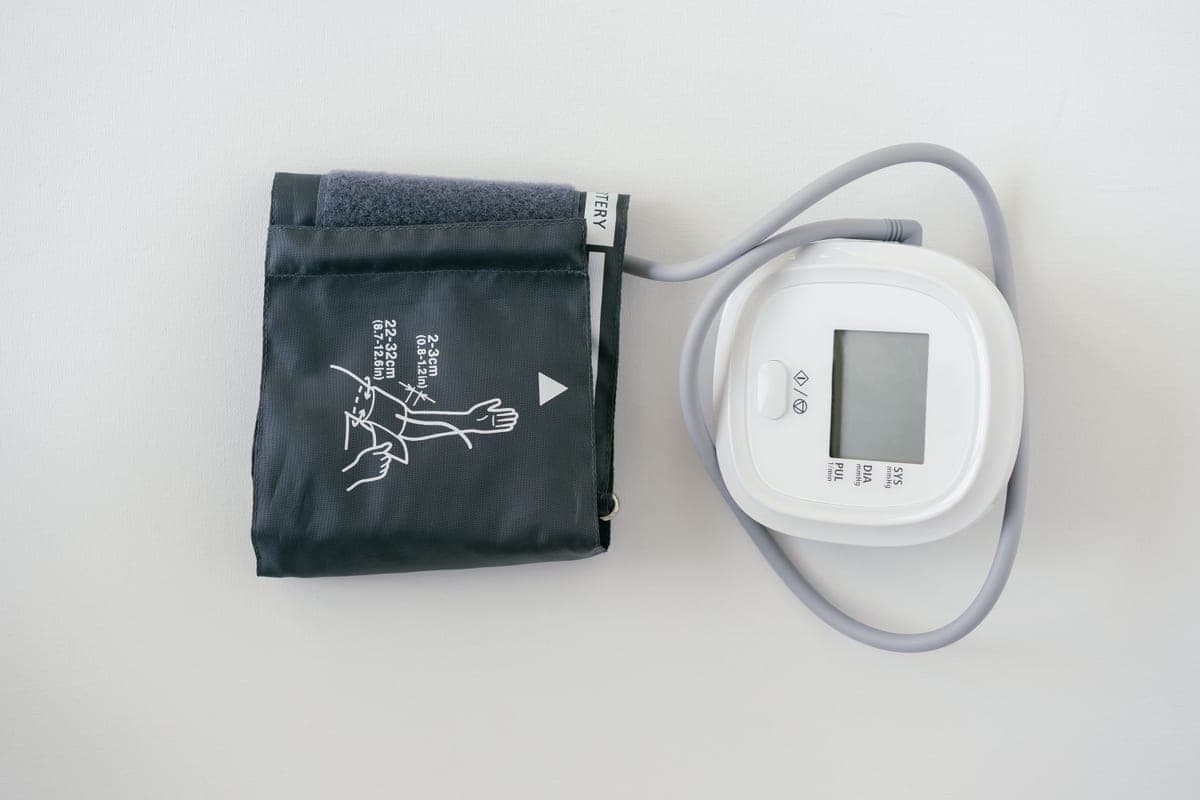 A digital blood pressure monitor beside its arm cuff