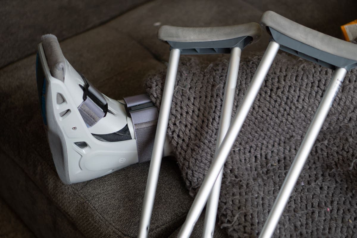 A walking boot and a pair of crutches resting beside a couch