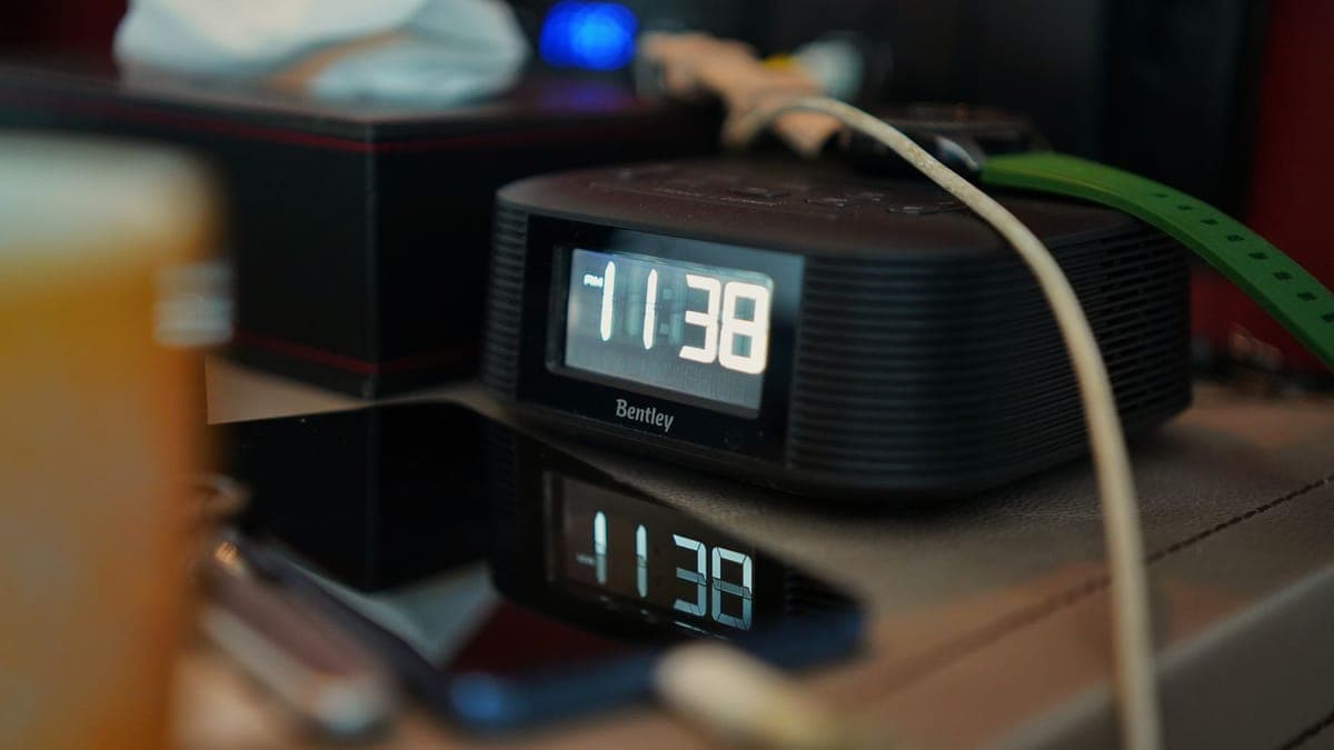 A digital clock with large white digits on a bedside table