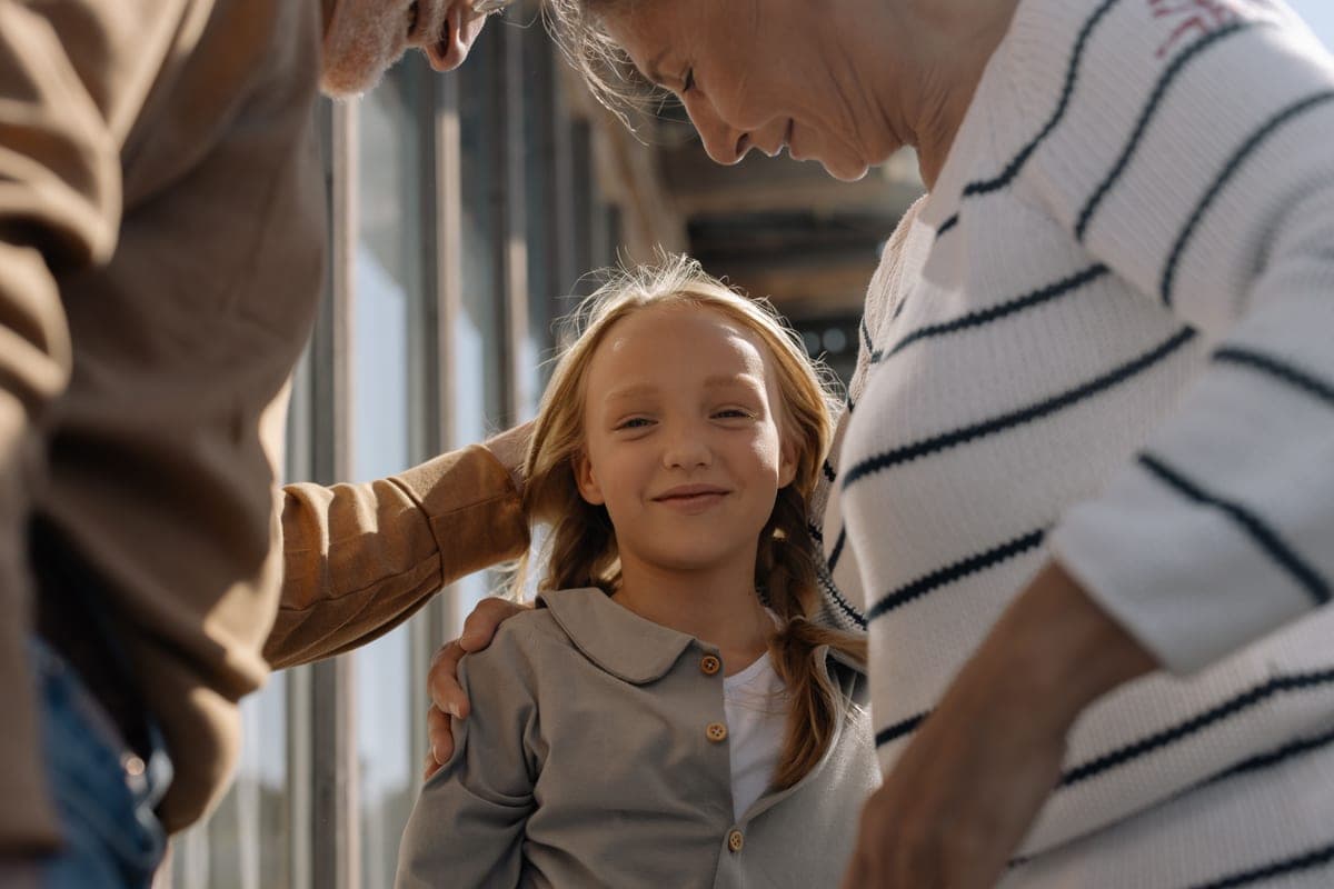 A child hugged by her grandparents