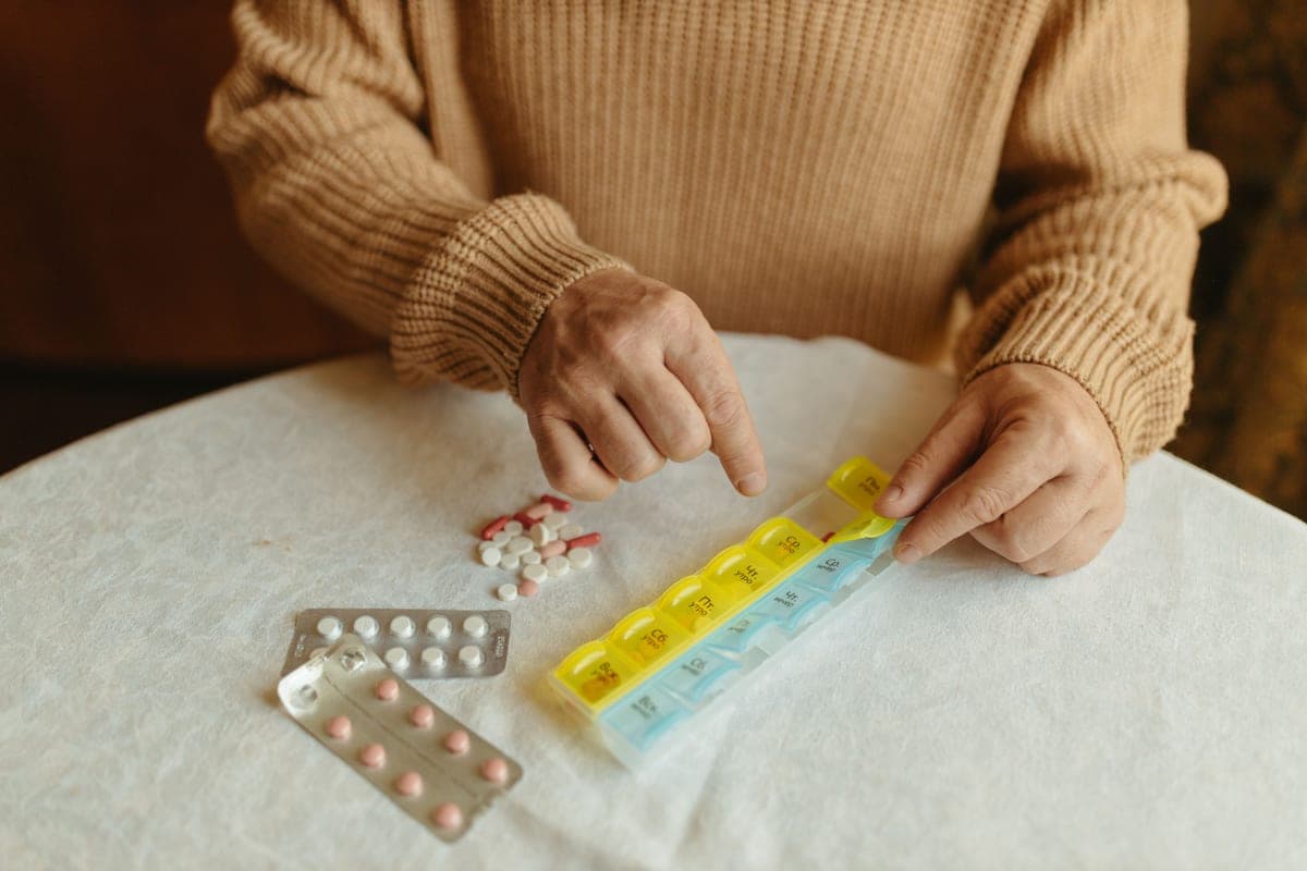 Hands sorting tablets into a weekly pill organizer