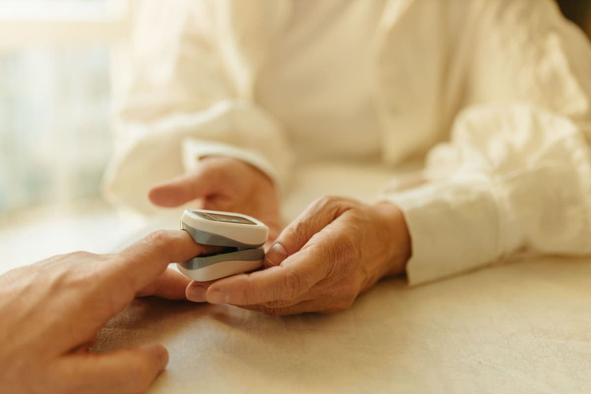 A fingertip pulse oximeter clipped to a finger at home