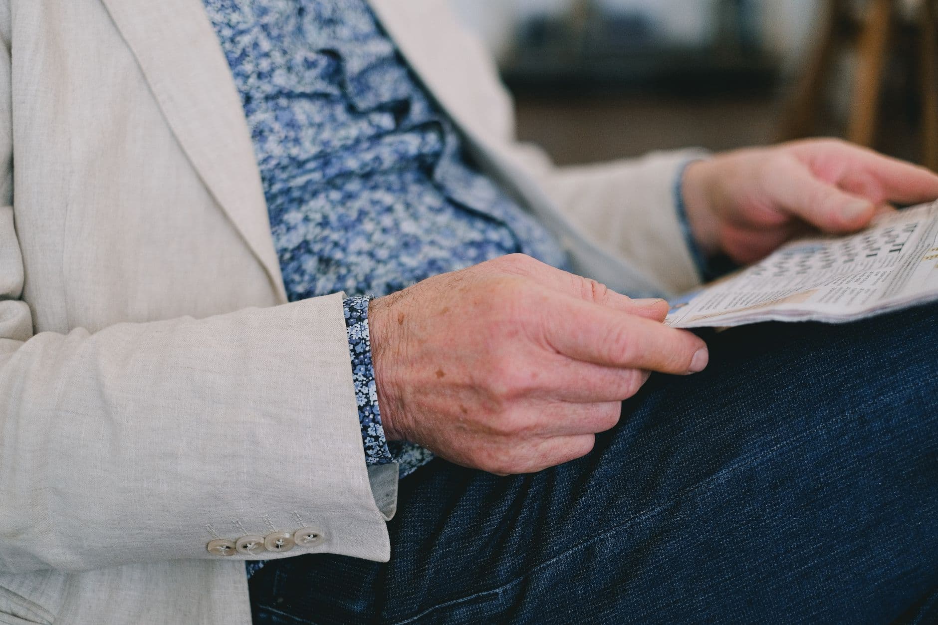 An older person's hands holding a folded newspaper
