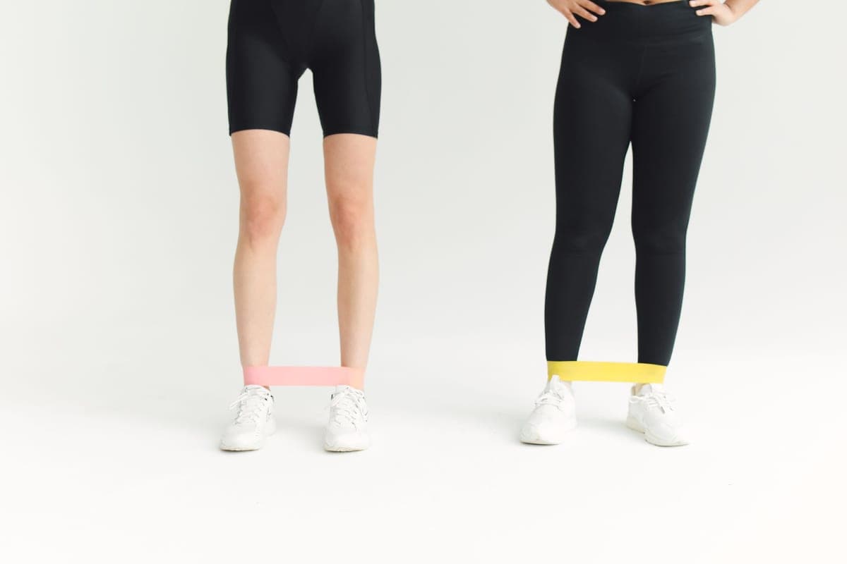 Two people exercising with resistance bands around their ankles
