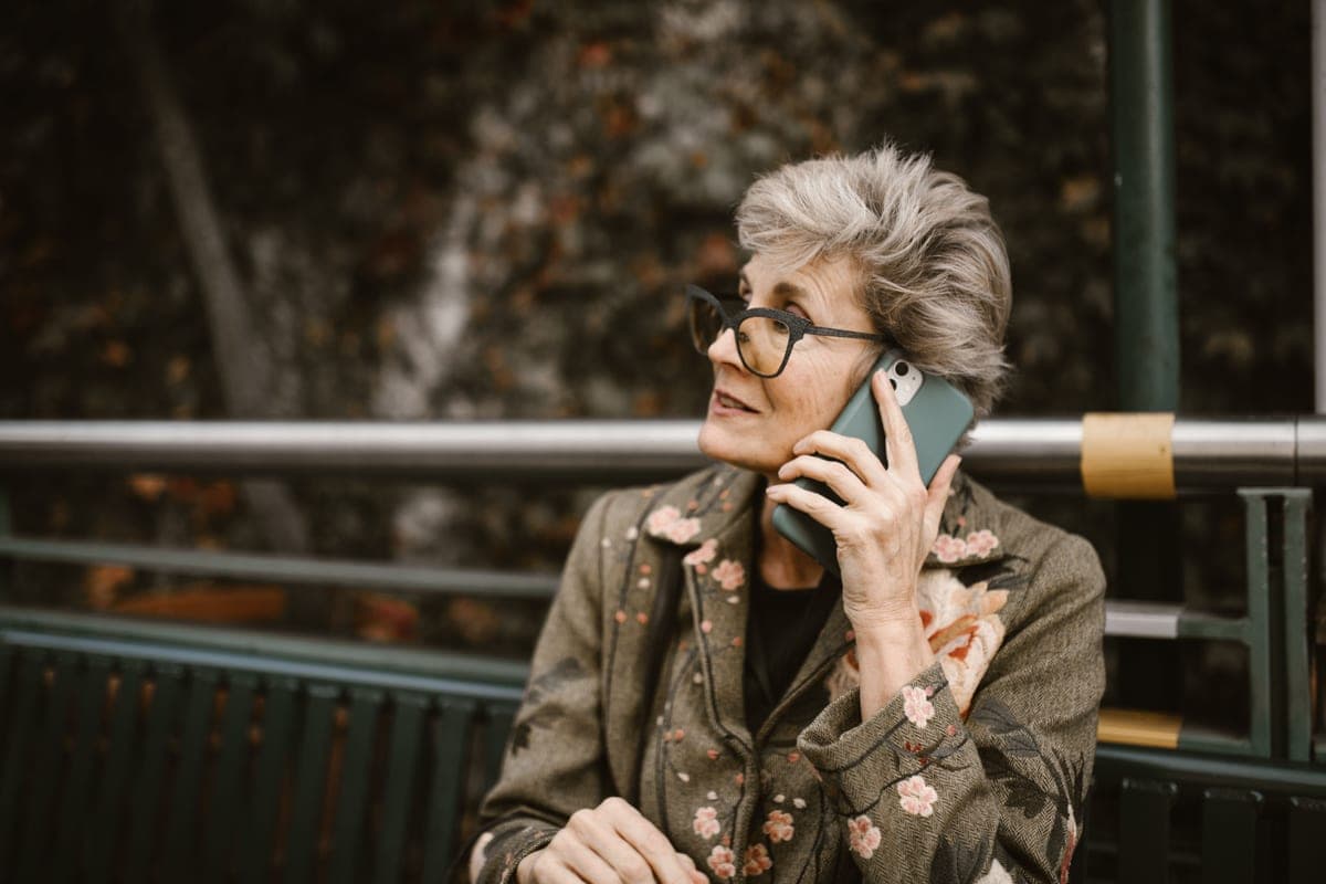 An older woman talking on a smartphone outdoors