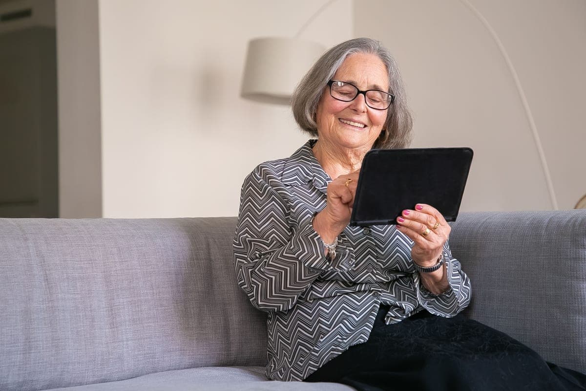 An older woman using a tablet on a sofa